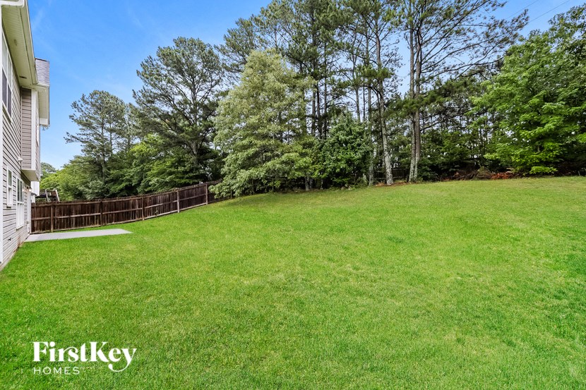 a backyard with a fence and a green lawn and trees