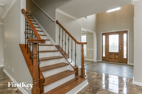 the foyer and entryway of a house with a staircase and a wooden door