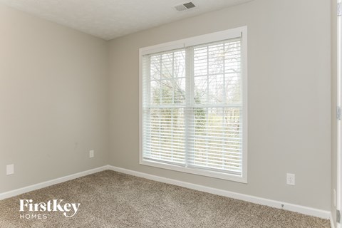 the second bedroom has a large window and beige carpet