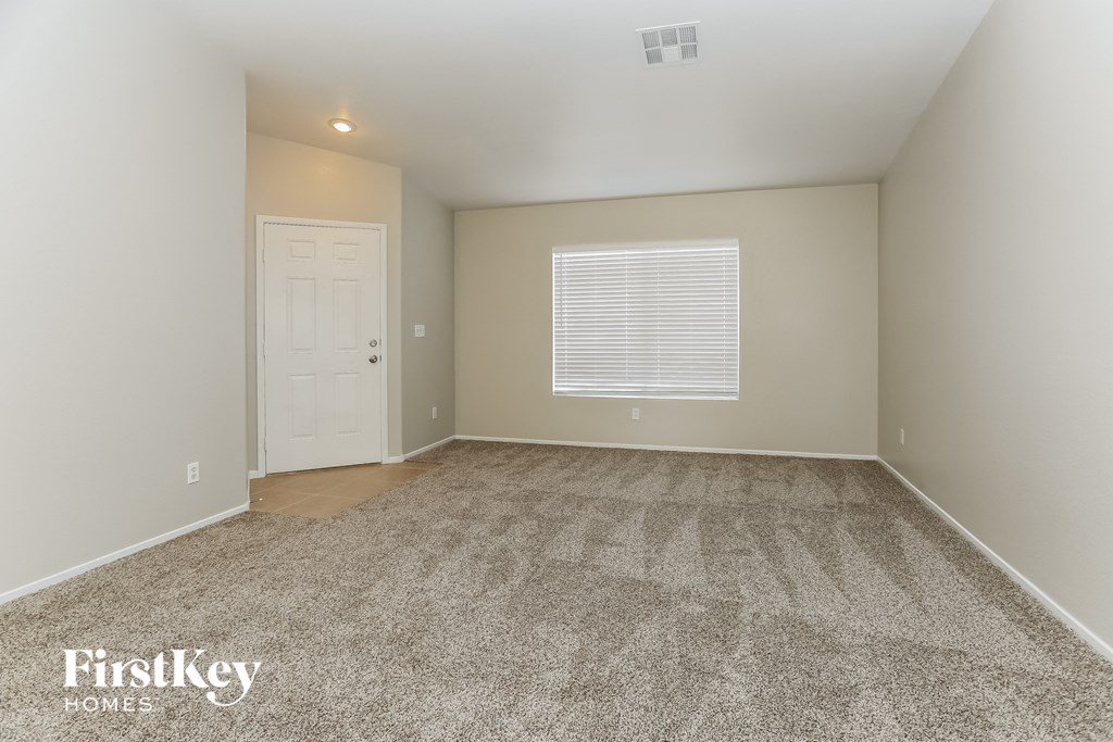 a spacious living room with carpet and a white door