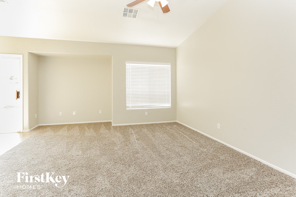 a empty living room with carpet and a window