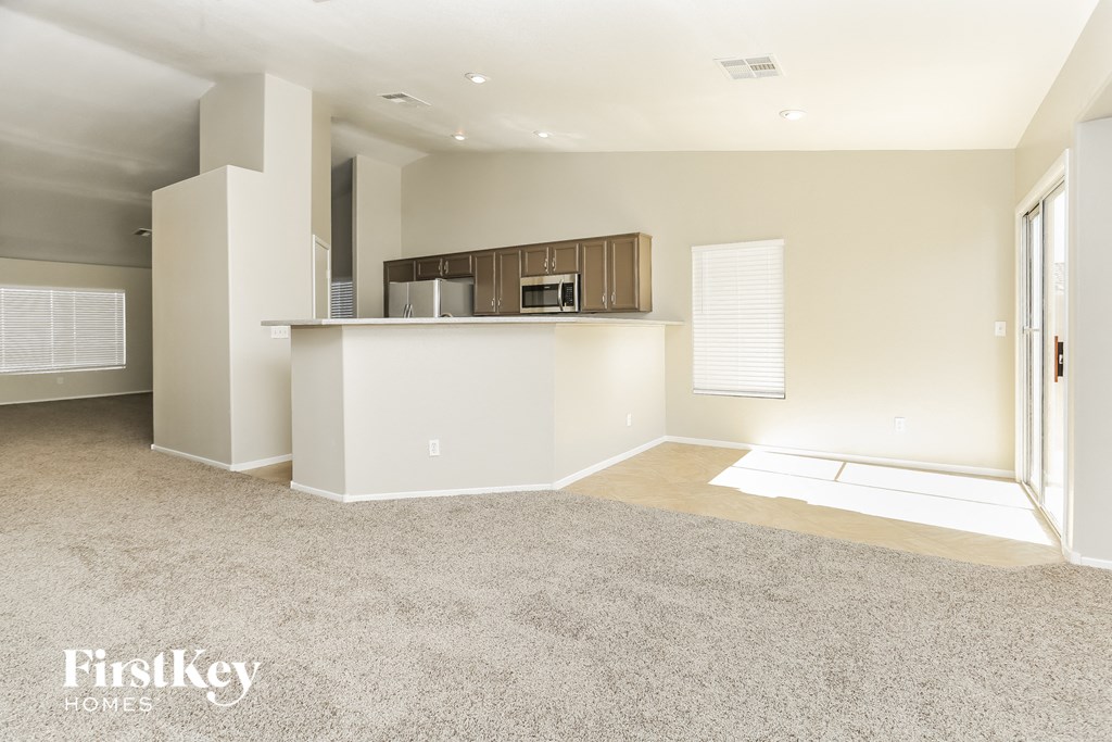 a living room with a kitchen and a carpeted floor