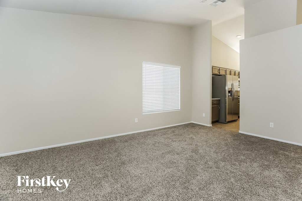 an empty living room with carpet and a kitchen