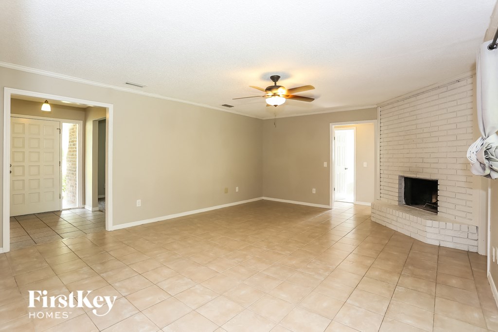 a living room with a brick fireplace and a ceiling fan