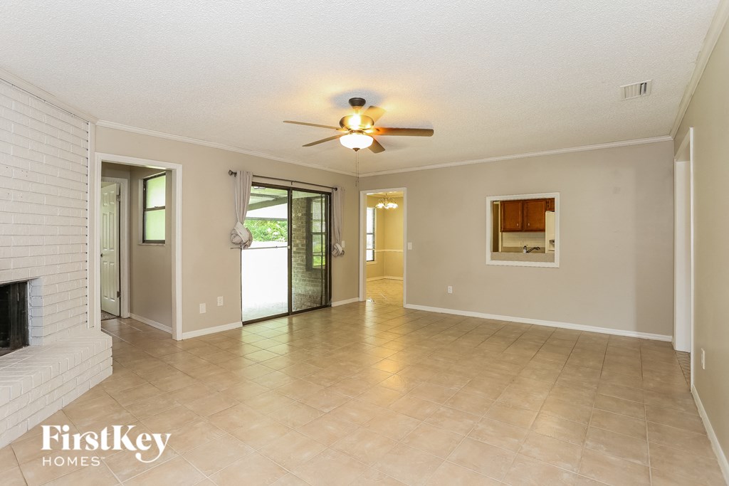 a spacious living room with a fireplace and a ceiling fan