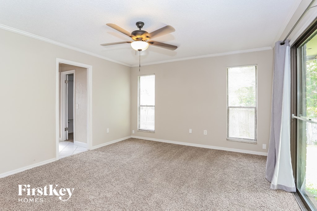an empty living room with a ceiling fan and a window