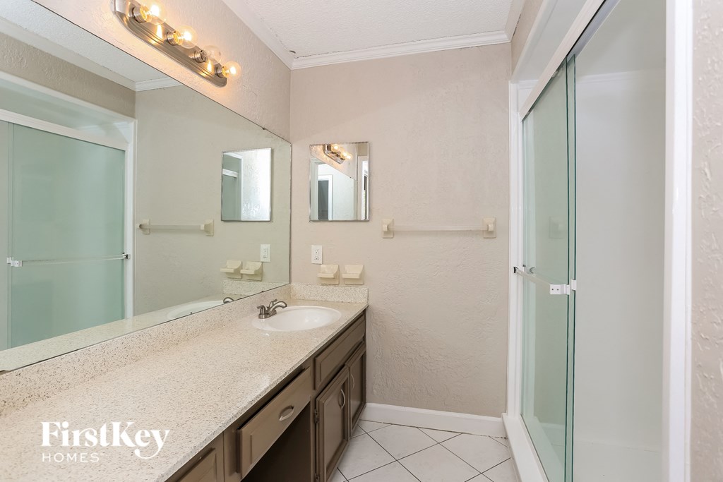 a bathroom with a sink and a shower and a mirror