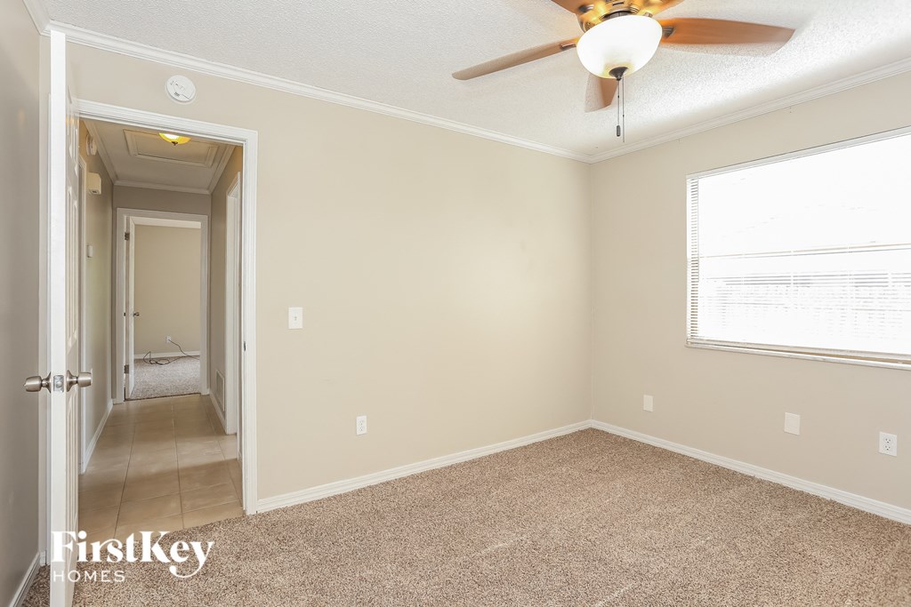 a empty room with a ceiling fan and a door to a hallway