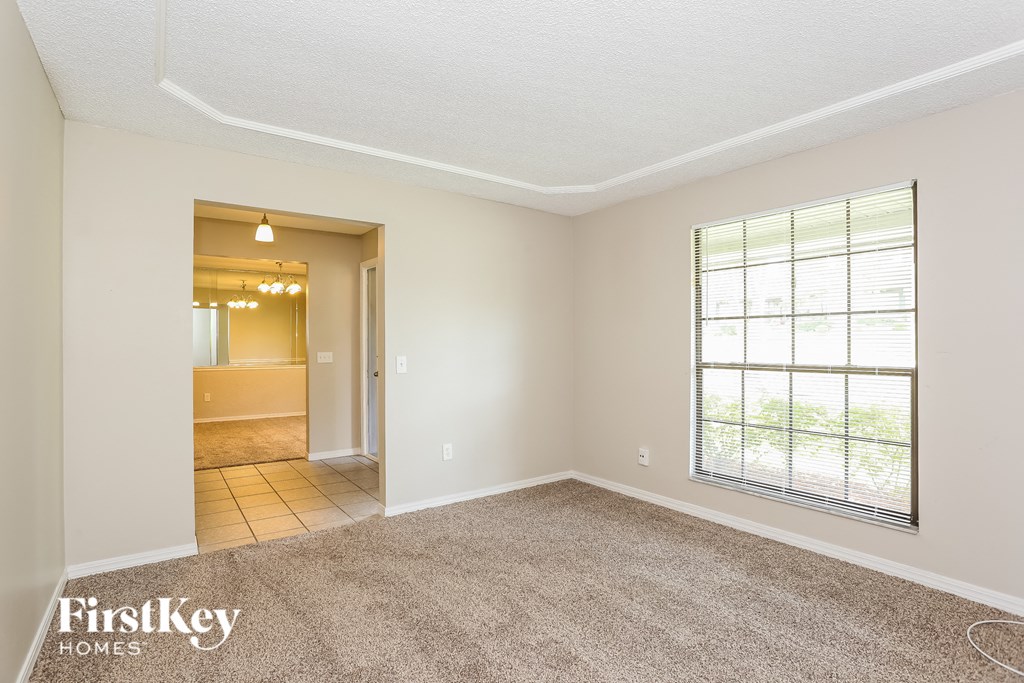 an empty living room with a large window and carpet