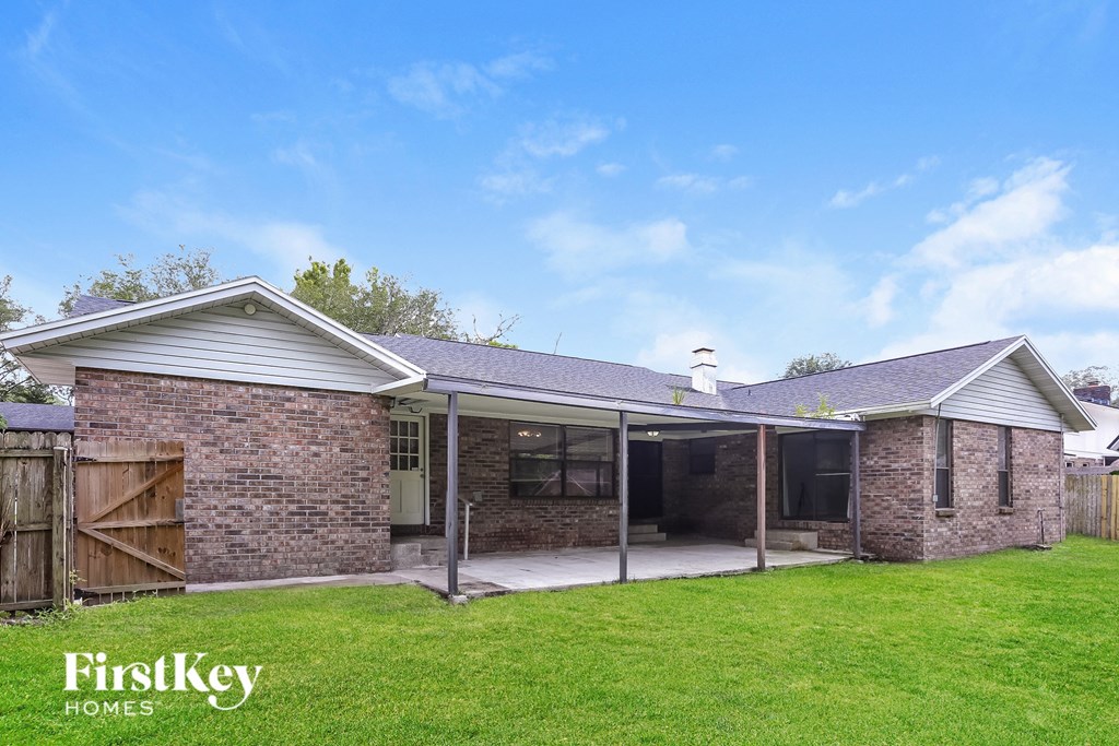 a small brick house with a patio and a grassy yard