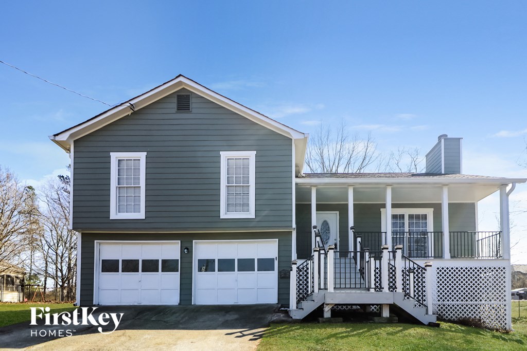 a gray house with white garage doors and a porch