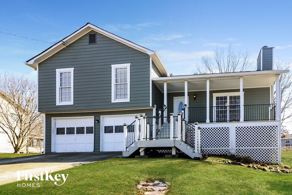 a gray house with white garage doors and a porch