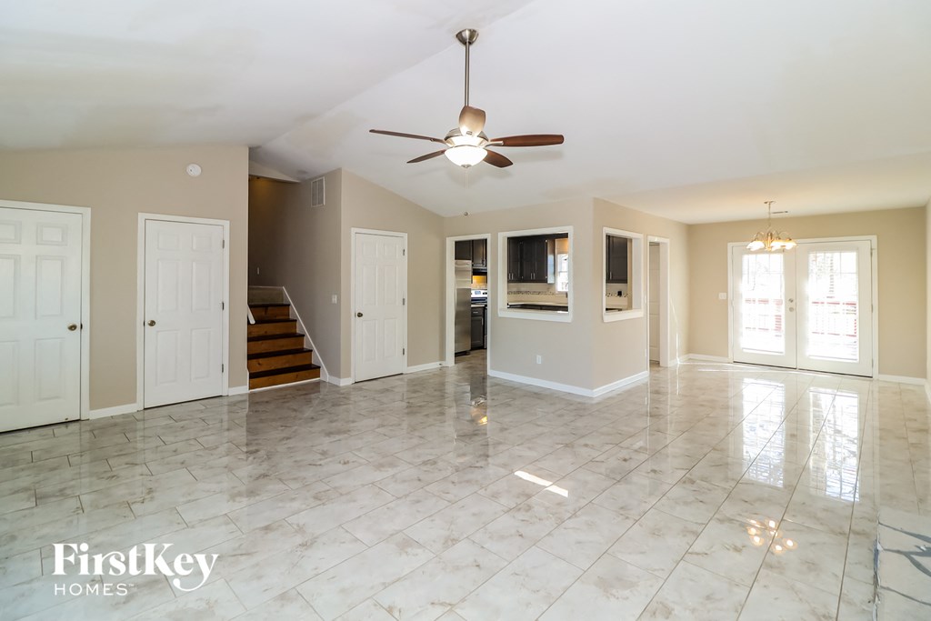 an empty living room with a ceiling fan and a tile floor