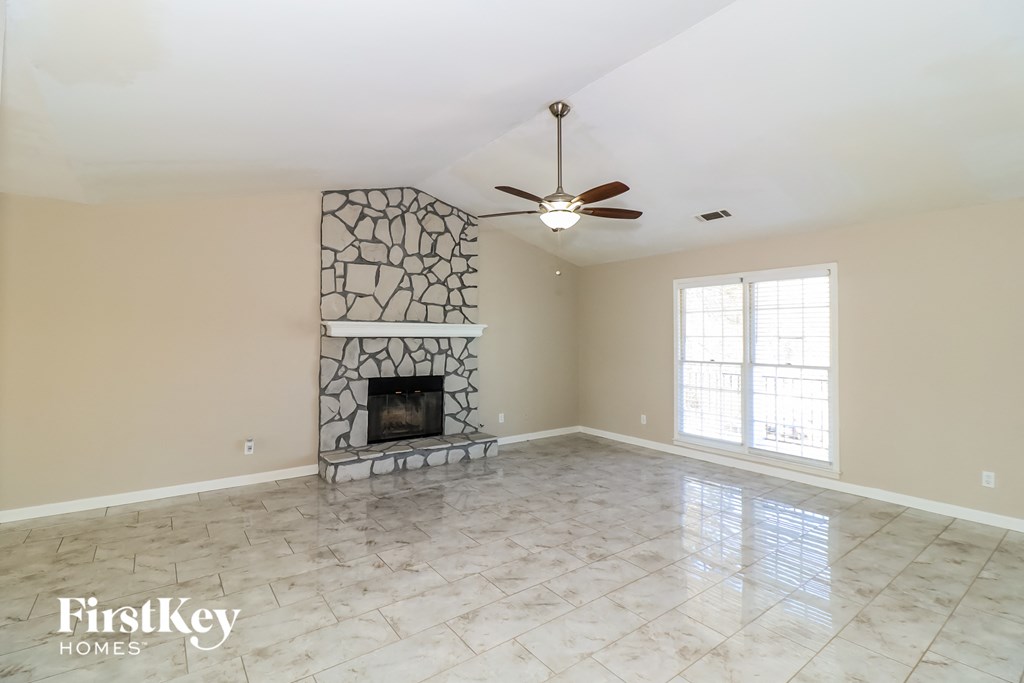 an empty living room with a fireplace and a ceiling fan