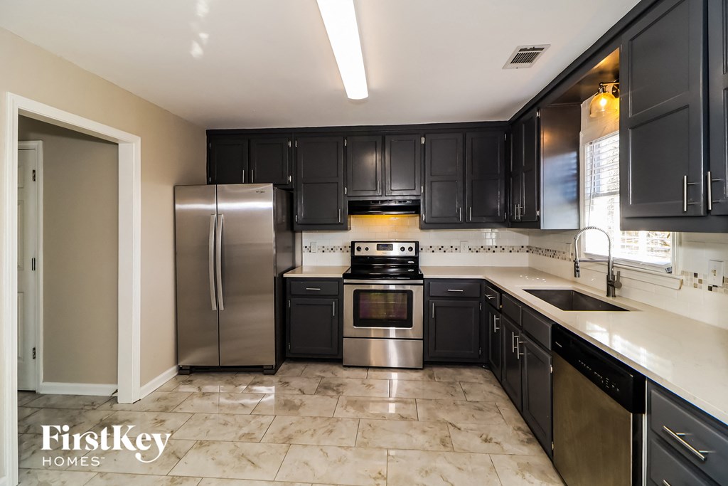a kitchen with black cabinets and stainless steel appliances