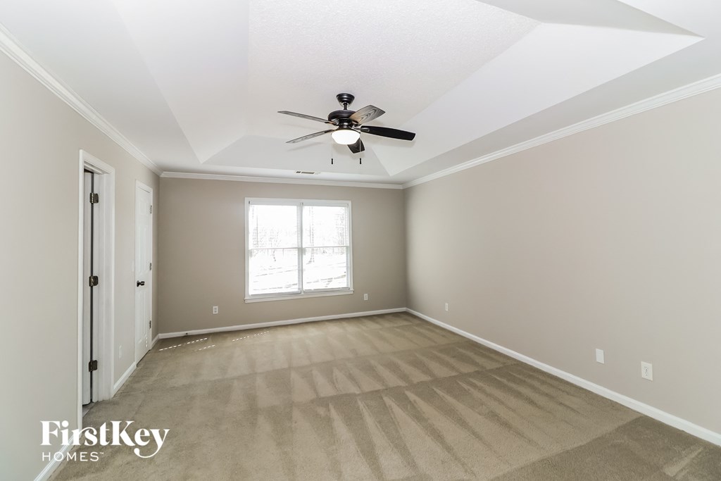 a empty living room with a ceiling fan and a window
