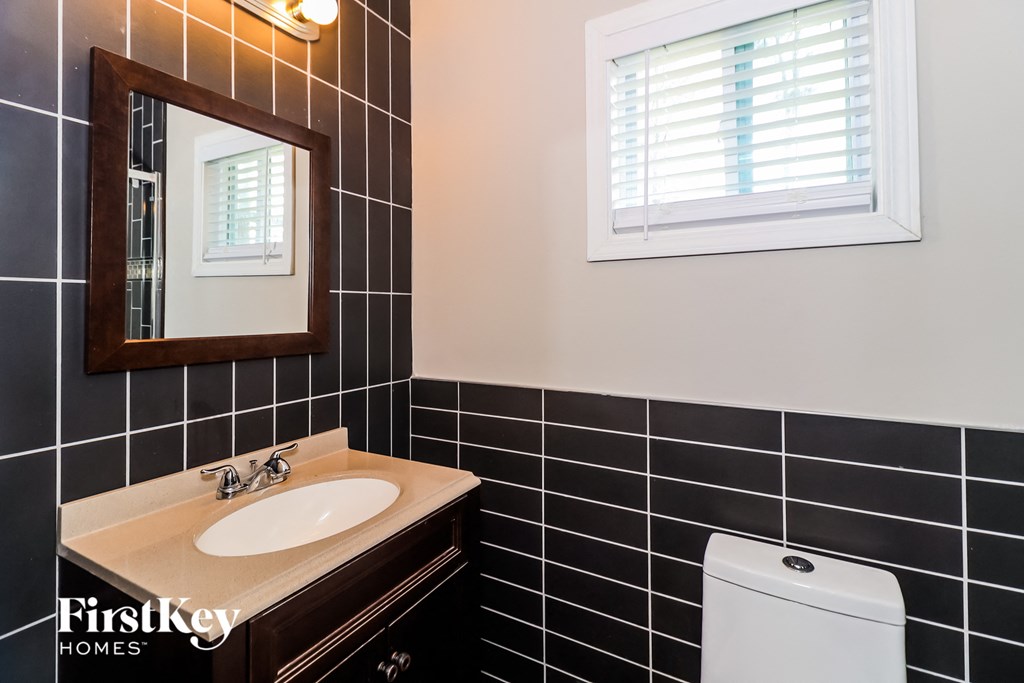 a bathroom with black tiles and a sink and a mirror