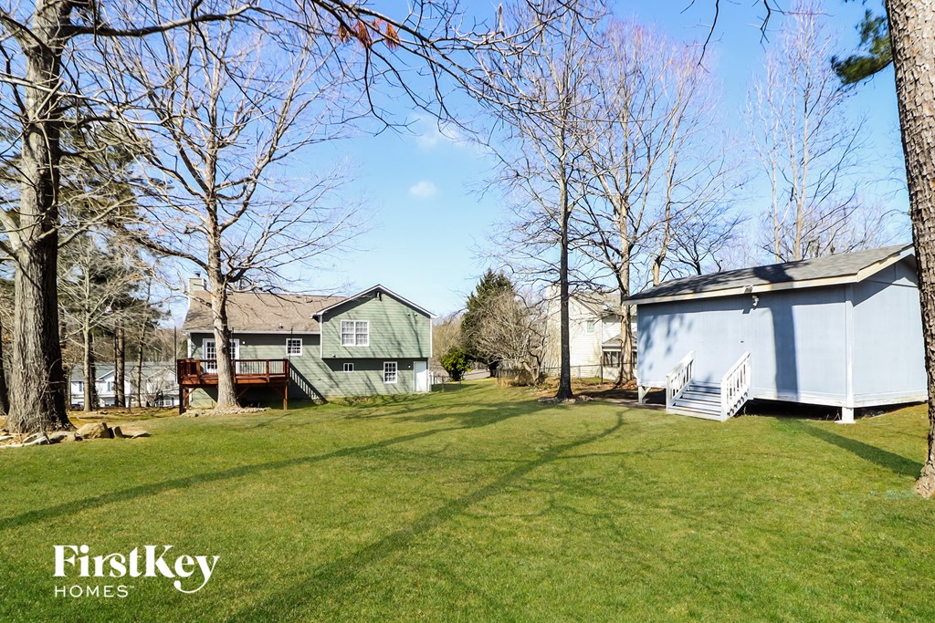 a backyard with a blue house and a white house and some trees