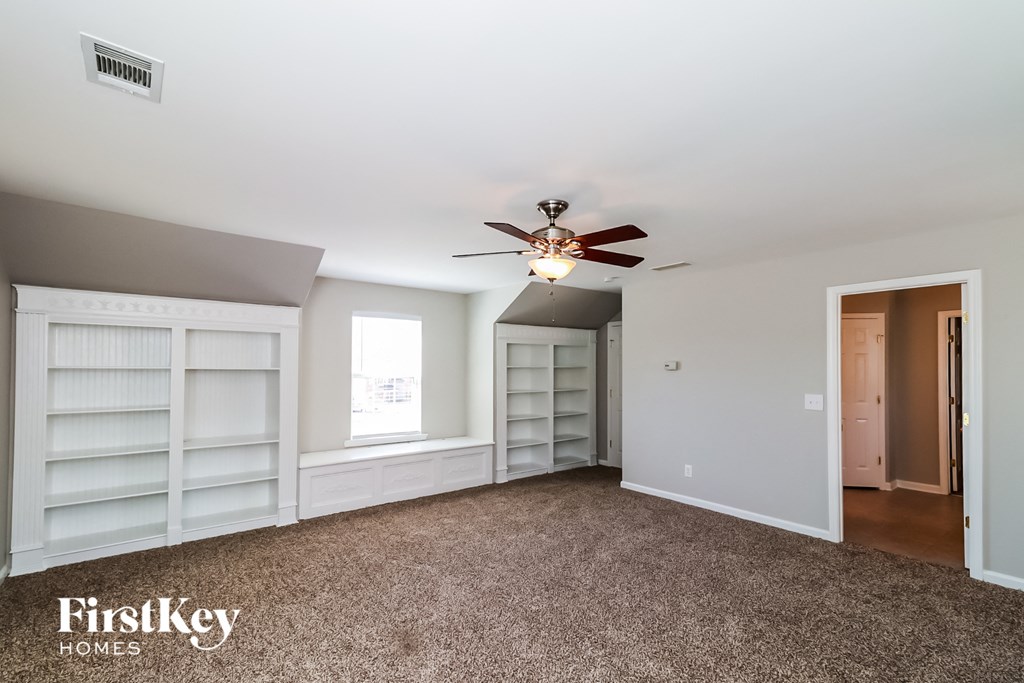 a bedroom with white shelves and a ceiling fan
