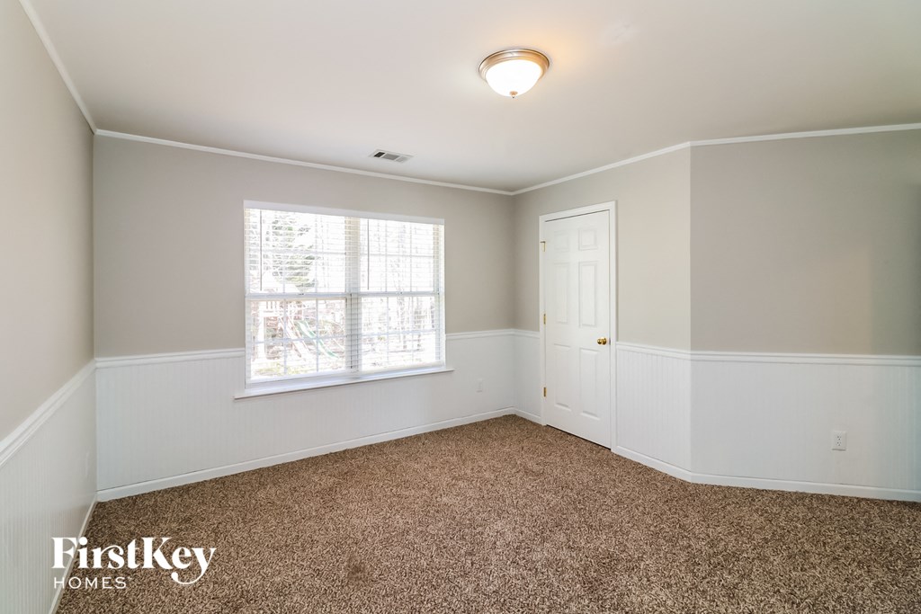 a bedroom with white walls and a window and a carpet
