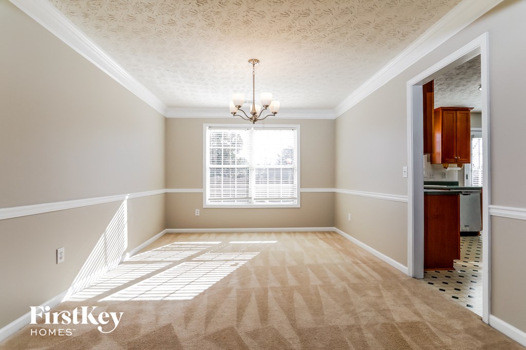 an empty dining room with a chandelier and a window