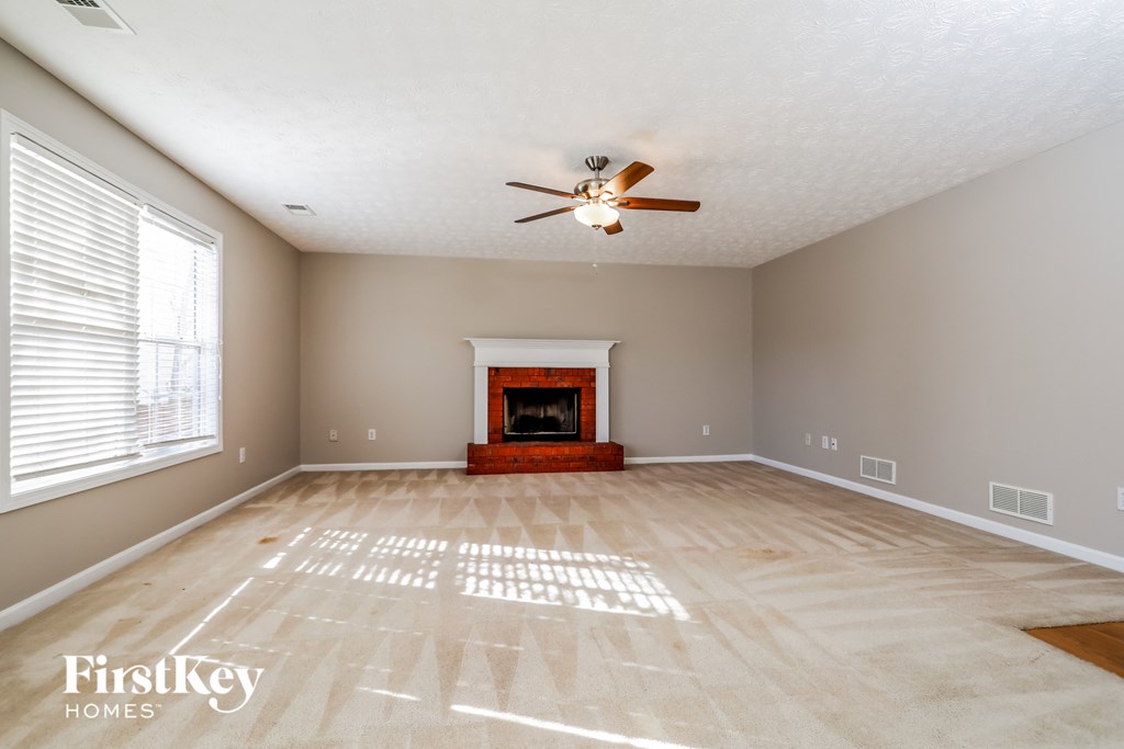 an empty living room with a fireplace and a ceiling fan