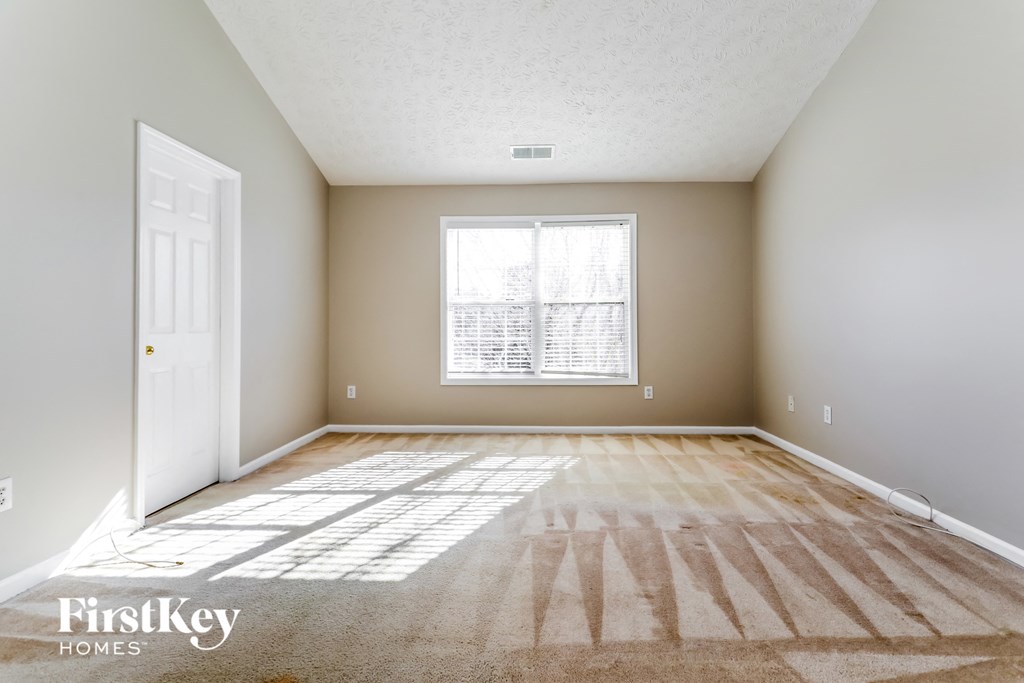 the living room of an empty house with a white door and a window