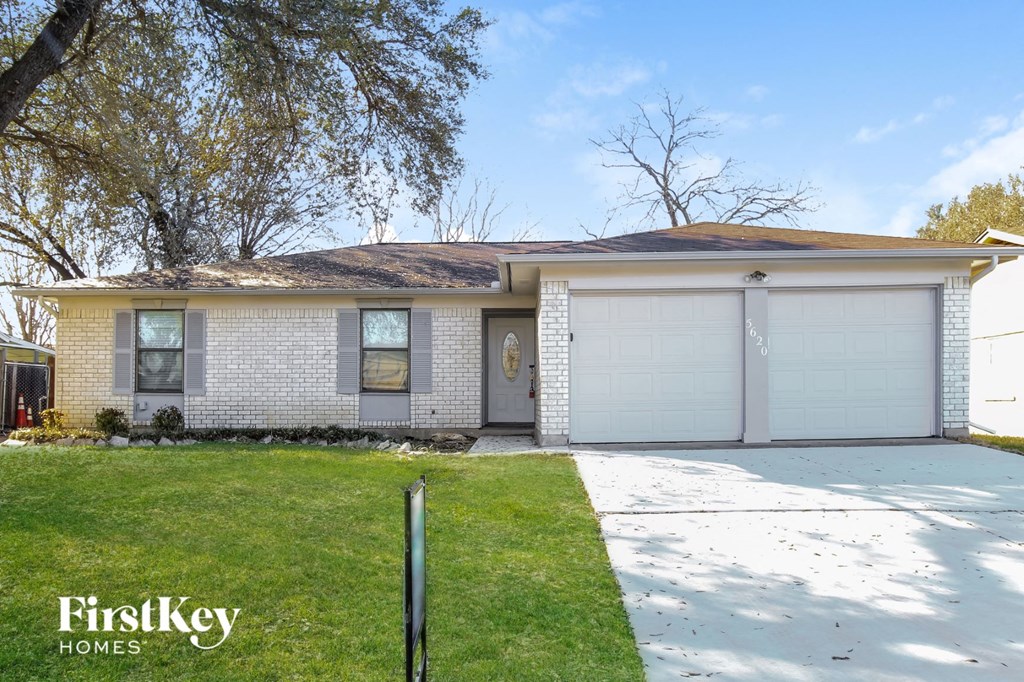 a white brick house with a lawn and a white garage door