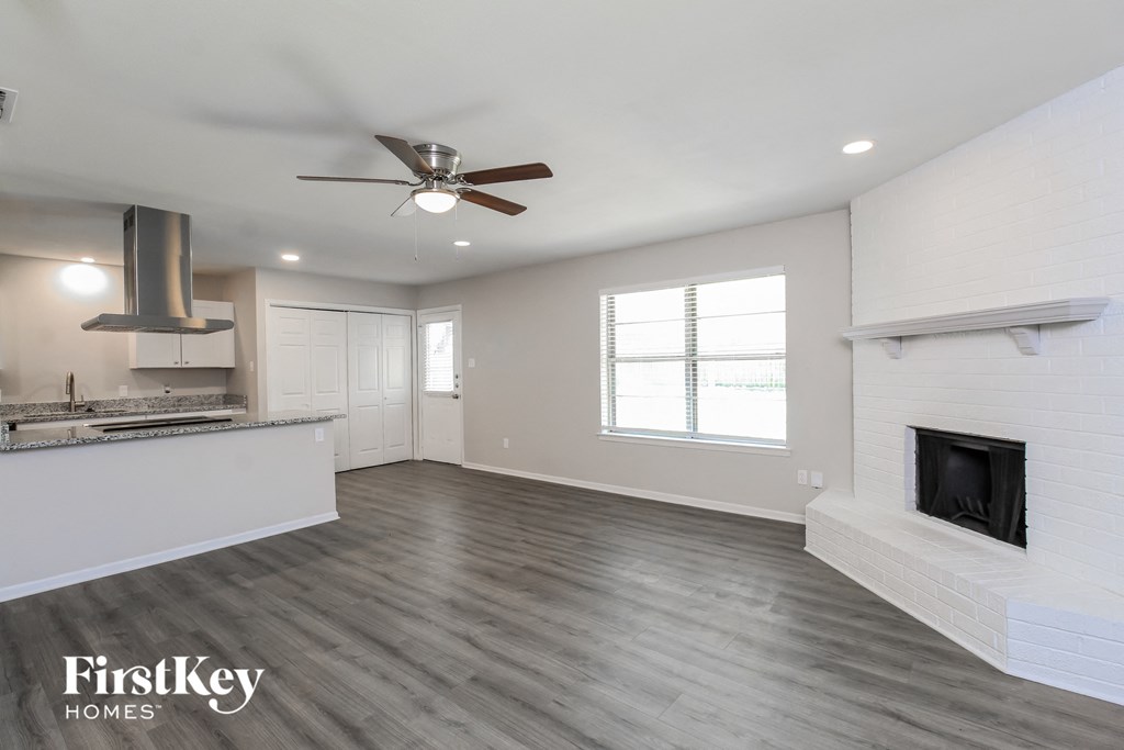 a kitchen and living room with a fireplace and a ceiling fan