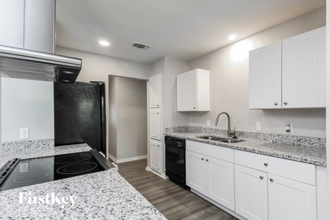 a kitchen with white cabinets and granite counter tops and a black stove and refrigerator