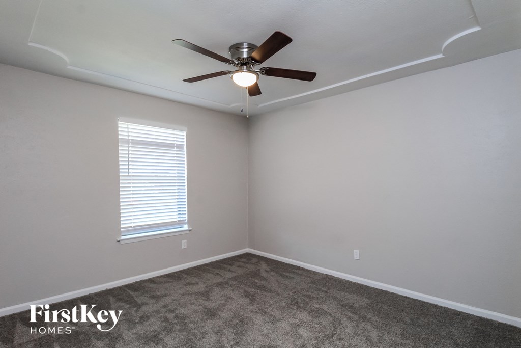 a empty room with a ceiling fan and a window