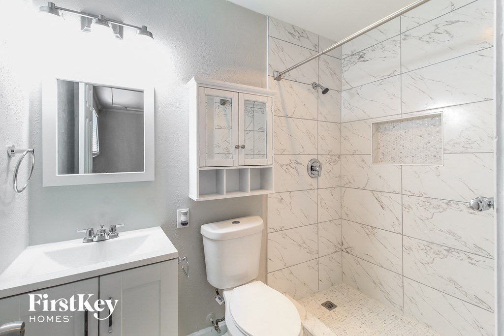 a bathroom with a toilet sink and shower and a mirror