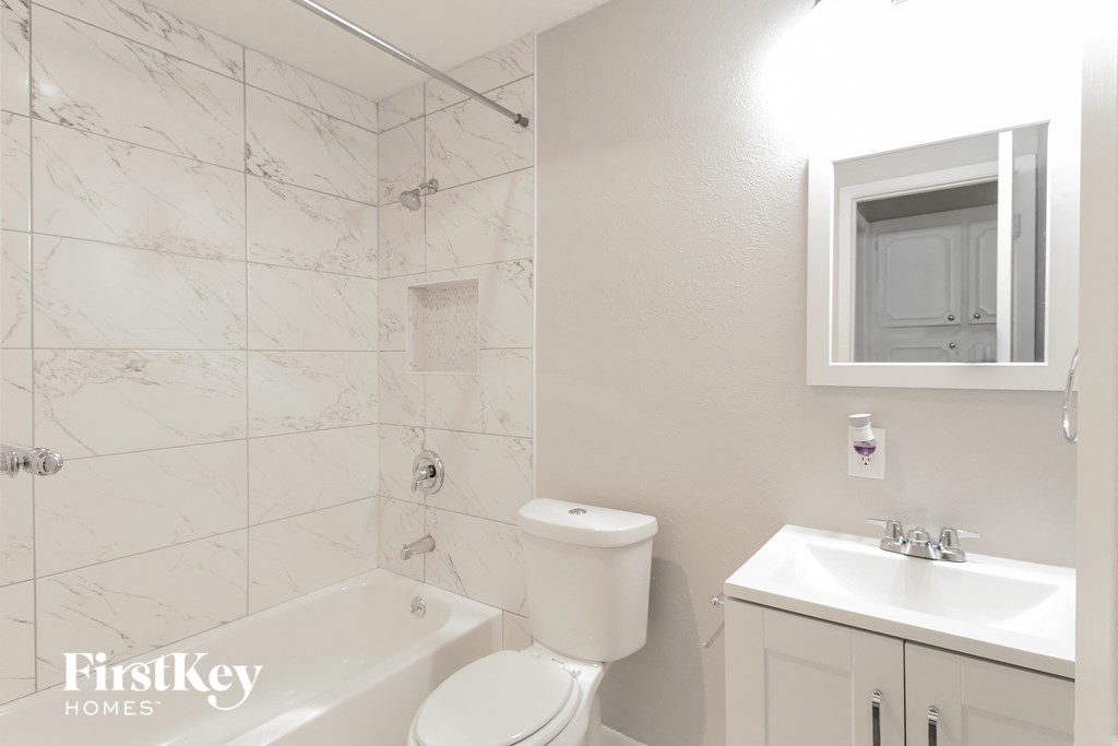 a bathroom with a toilet sink and tub and a mirror
