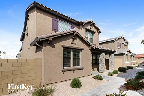 a beige house with purple window shutters and a stone wall