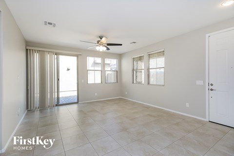 a spacious living room with tile flooring and a ceiling fan