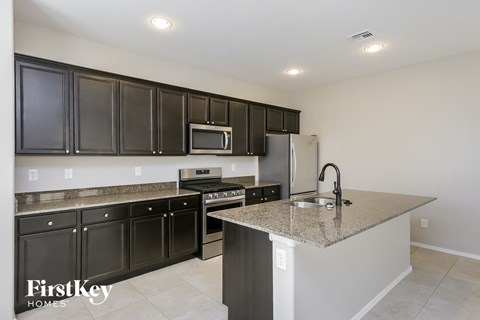 a kitchen with granite counter tops and black cabinets and stainless steel appliances
