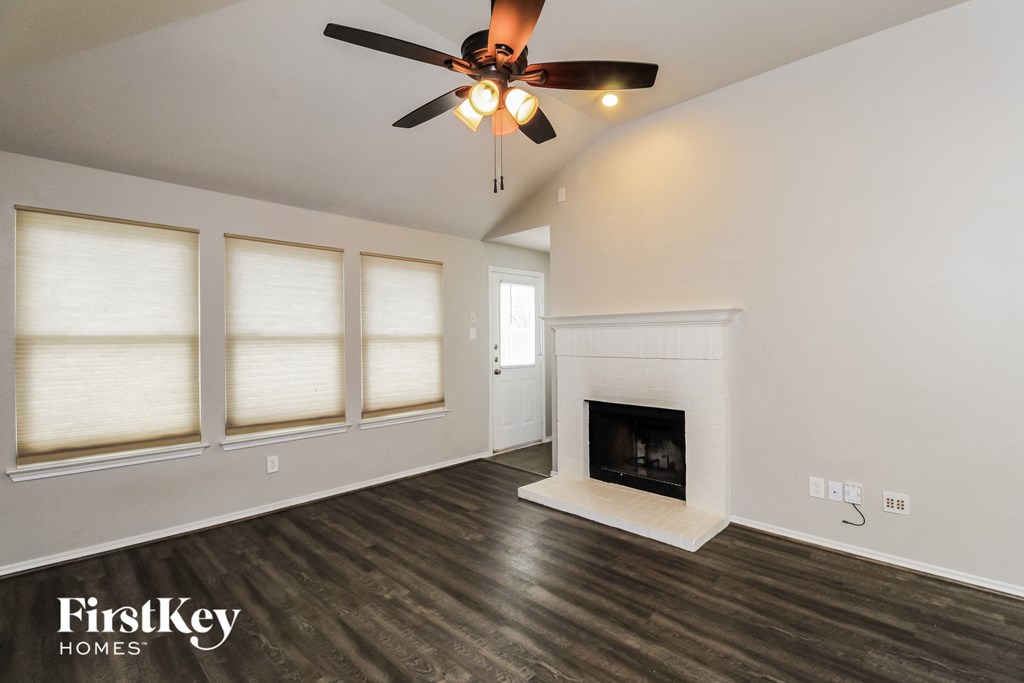 A living room with a fireplace and a ceiling fan.