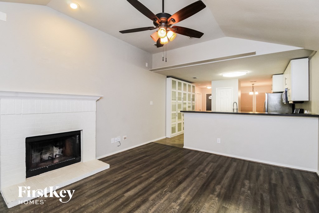 A spacious living room with a fireplace and a ceiling fan.