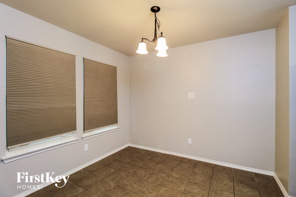 A room with a light fixture, two windows with blinds, and a tiled floor.