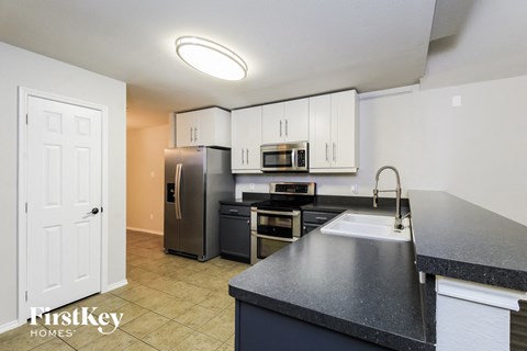 A kitchen with a sink, refrigerator, and cabinets.