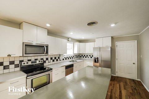 a large kitchen with white cabinets and stainless steel appliances