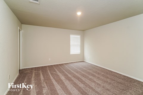 a spacious living room with carpet and white walls