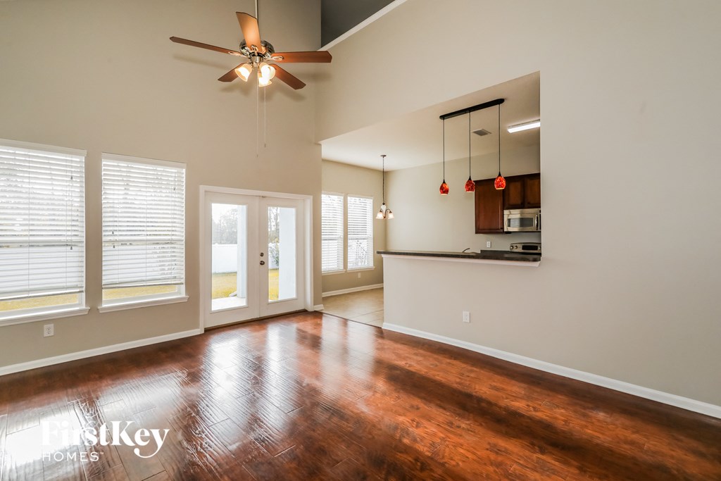 A spacious room with a ceiling fan and wooden flooring.