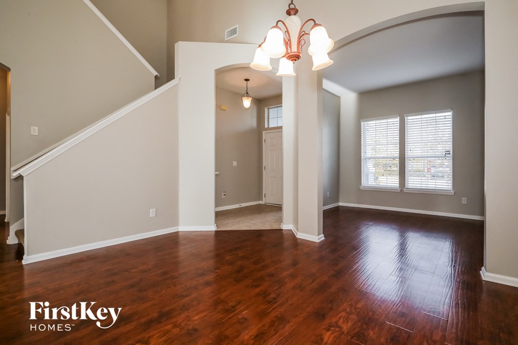 A well-lit, spacious room with wooden floors and a staircase.