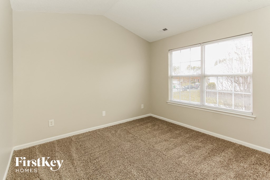 a bedroom with a carpeted floor and a large window