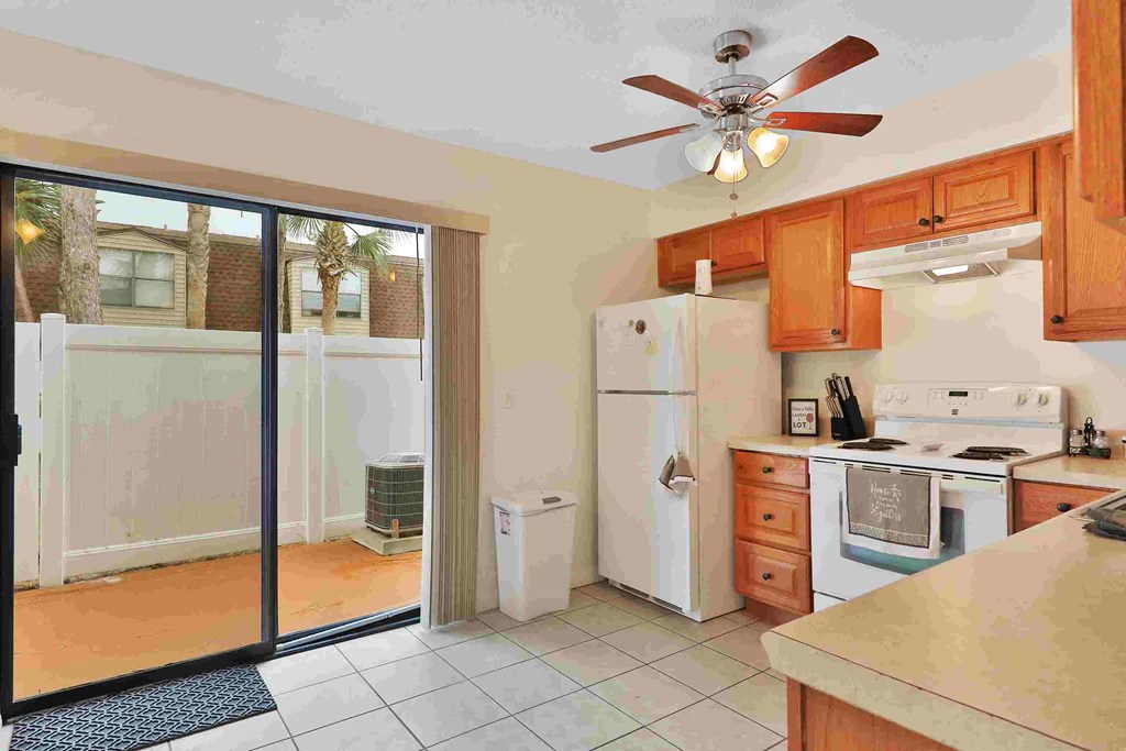 a kitchen with a door to the yard and a white refrigerator