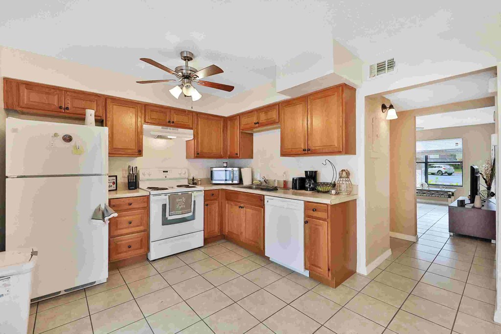 a large kitchen with white appliances and wooden cabinets