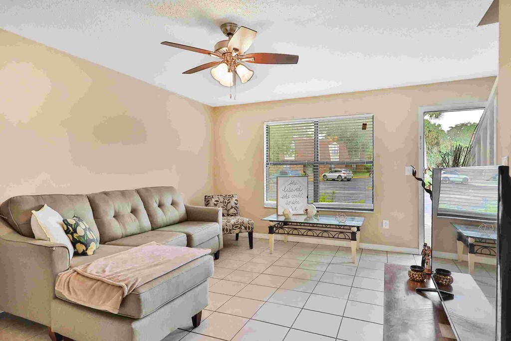 a living room with couches and a ceiling fan