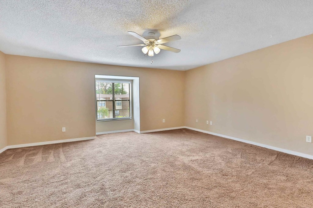 an empty living room with a ceiling fan and a window