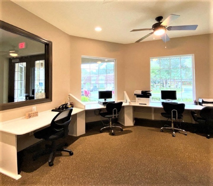 two computer desks in a room with a ceiling fan